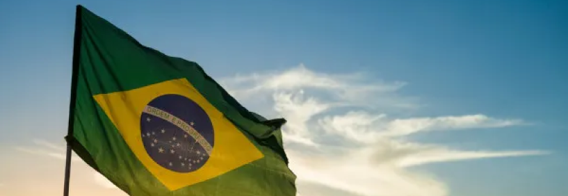 Bandeira do Brasil hasteada com os edifícios modernos de Balneário Camboriú ao fundo.