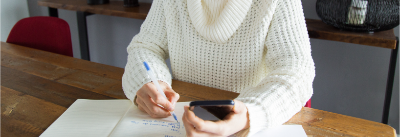 Mulher jovem sentada à mesa, concentrada ao analisar documentos e planilhas financeiras, simbolizando o planejamento do orçamento antes de um financiamento imobiliário.