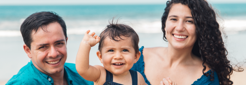 Família feliz caminhando na praia em Santa Catarina, mostrando os benefícios de conseguir financiamento para morar no litoral com mais qualidade de vida.